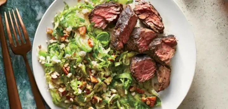 Brussels Sprouts Salad with Coffee-Rubbed Steak on a white plate