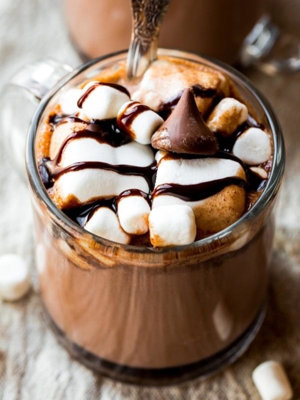 A glass of hot chocolate with marshmallow and chocolate chip on top of it