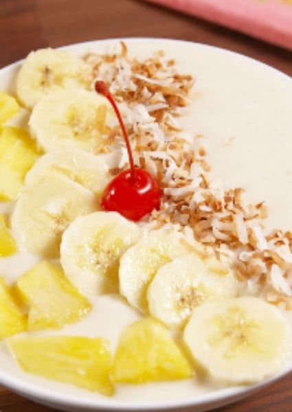 Pina Colada Smoothie Bowl with banana slices, coconut flakes and cherry 