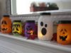 Five different shapes and colors of Jack O’Lanterns mason jar on a mantel.