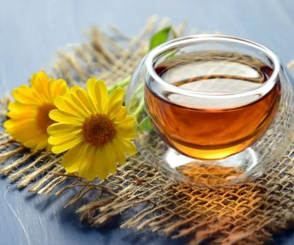 Clear glass bowl of honey beside yellow flower