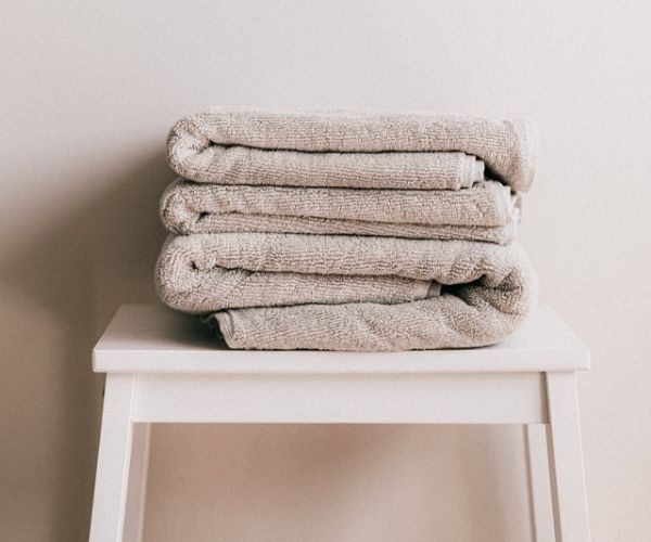 Stack of fresh grey towels on a white stool